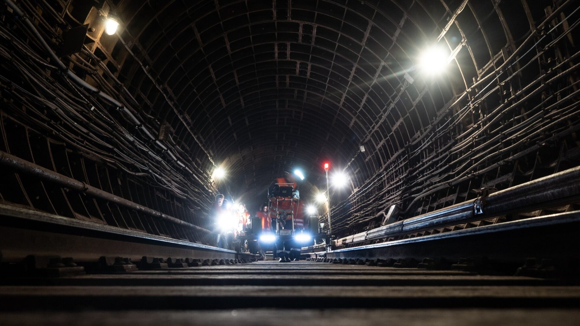 Освітлений перегінний тунель Київського метрополітену з рейками та службовою технікою всередині