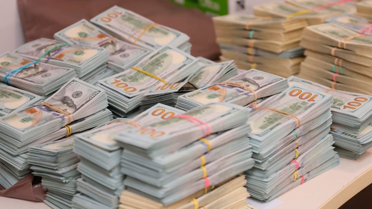 Великі стоси стодоларових купюр, перетягнутих гумками, на поверхні