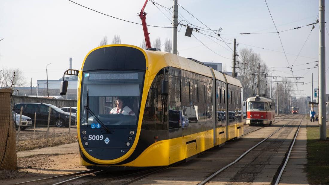 Сучасний жовто-чорний трамвай рухається рейками