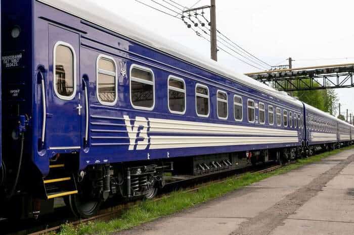 синій пасажирський вагон «Укрзалізниці», що стоїть на залізничній колії