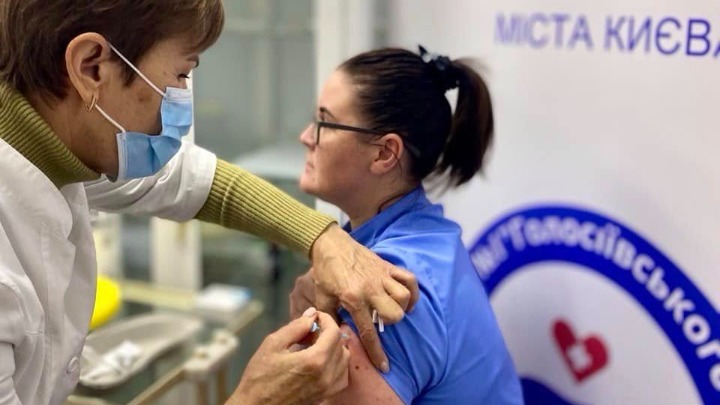 Медична працівниця робить щеплення жінці у блакитній формі