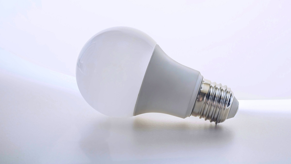 Біла LED-лампочка з металевим цоколем, покладена горизонтально на світлому фоні