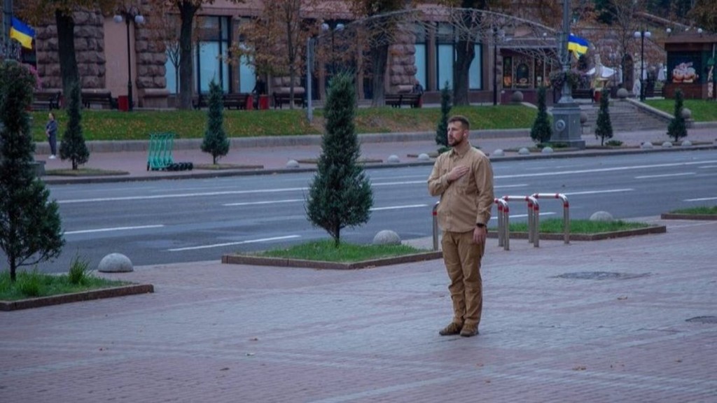 Увага, водії: де перекриють дороги в Києві 24 вересня Чоловік у світло-коричневій формі стоїть на тротуарі в центрі міста з рукою на серці