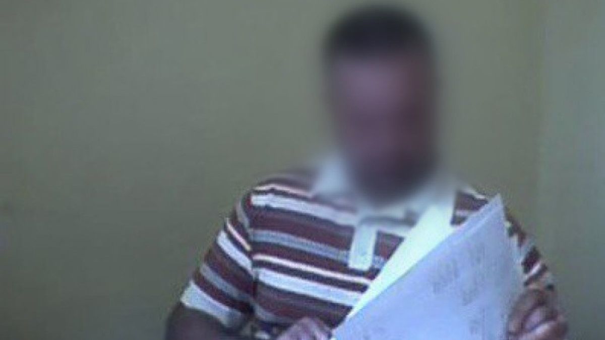 Затуманене зображення чоловіка в спортивній футболці, що тримає папірки в руках, на тлі світлої стіни, ймовірно у будівлі або офісі.