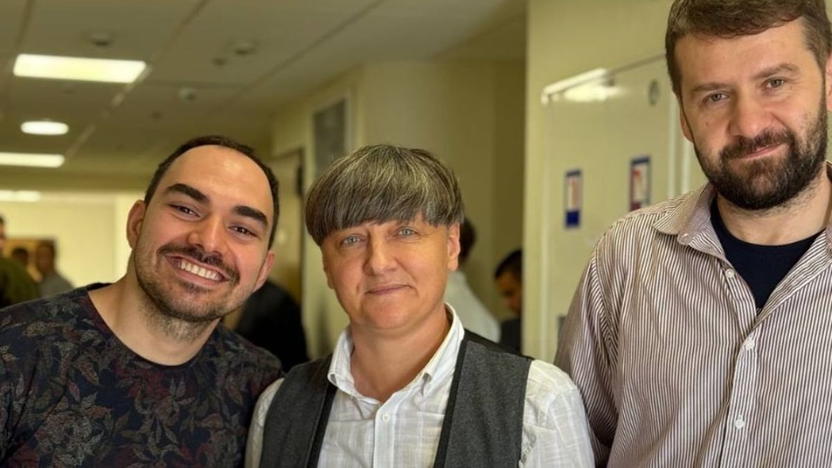 Троє людей у коридорі суду під час засідання апеляційного суду, вони позують для фото та усміхаються