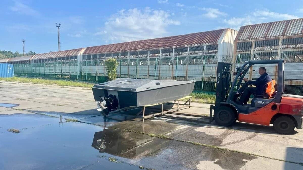 Навантажувач перевозить невеликий безпілотний катер сірого кольору на платформі