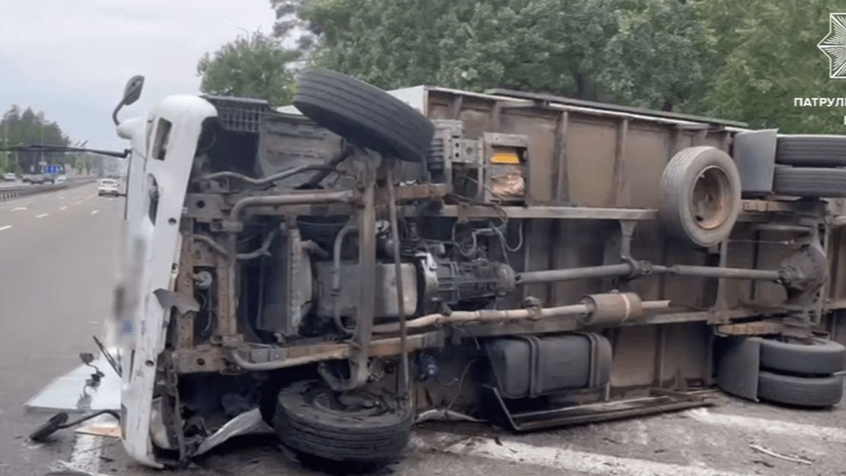 Білий вантажний автомобіль перекинувся на бік на трасі, видно пошкоджене днище та колеса