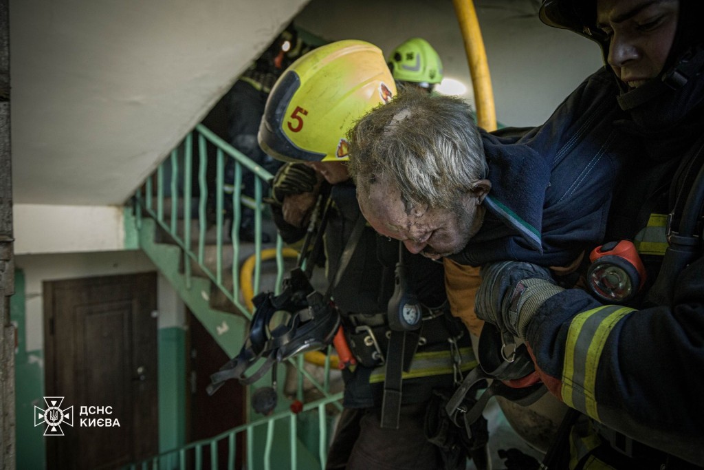 Пожежники виводять постраждалого чоловіка з під’їзду