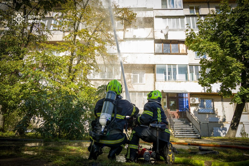 Двоє пожежників гасять пожежу зі шлангом