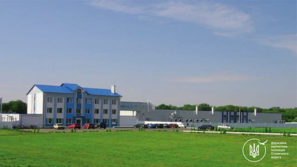 Біло-блакитна адміністративна будівля з синім дахом і виробничий корпус на фоні зеленого поля