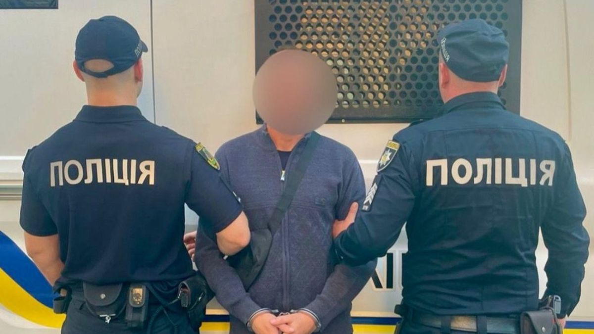 Поліція затримує підозрюваного, чоловіка у темному одязі, на задньому фоні поліційний автомобіль.