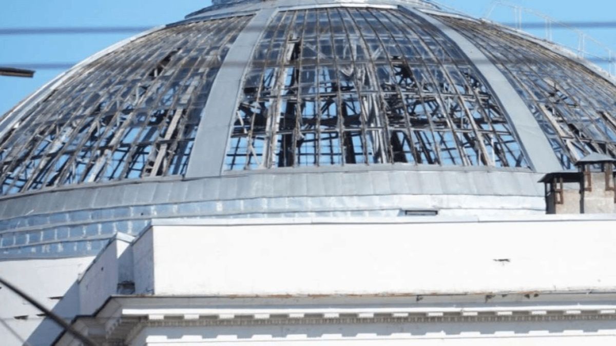 Пошкоджена будівля з розбитим скляним куполом у центрі Києва під час обстрілу, зруйновані вікна та руйнування на даху.