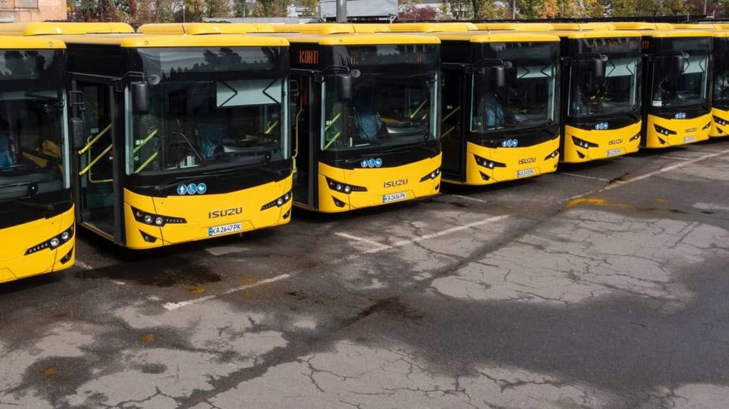 Київ отримав 30 нових автобусів: 20 уже працюють на маршрутах (фото) Ряд нових жовтих автобусів ISUZU на стоянці, видно їхні передні частини.
