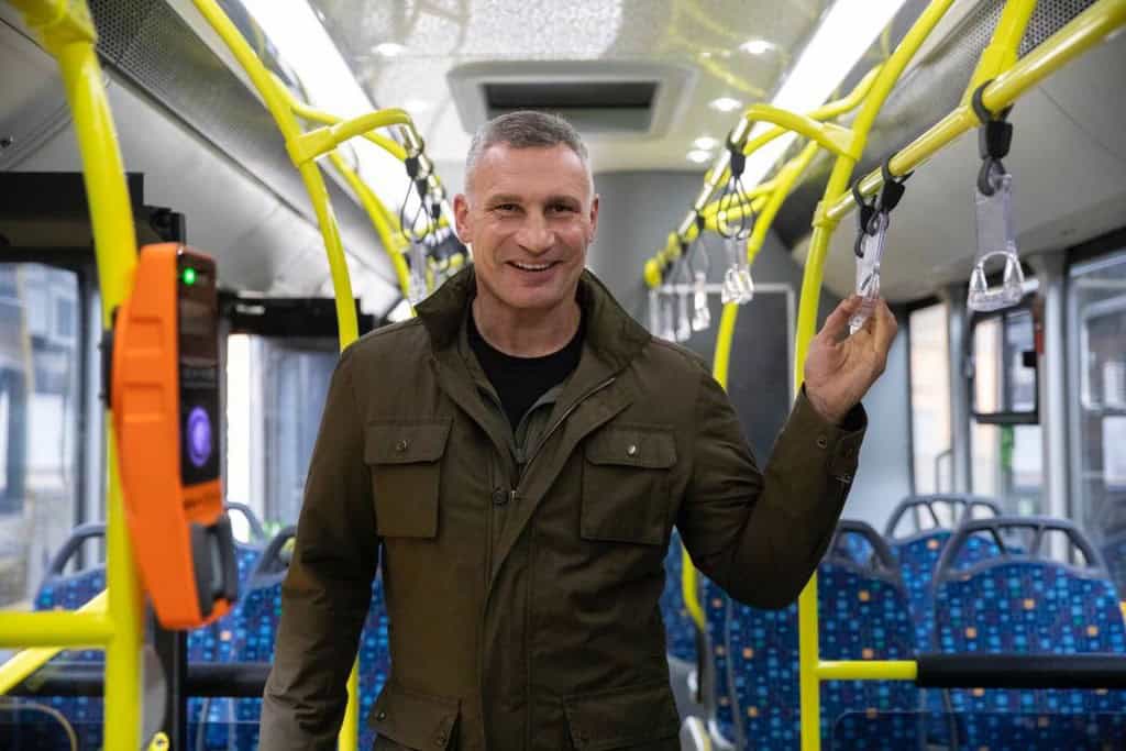 Київ отримав 30 нових автобусів: 20 уже працюють на маршрутах (фото) Мер Києва усміхається, стоячи у салоні нового автобуса біля поручнів