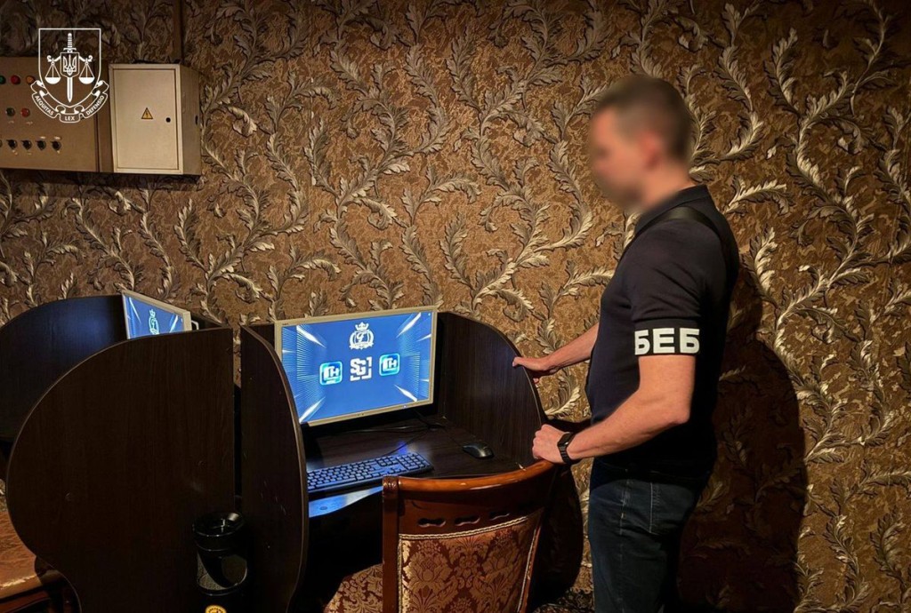 Правоохоронець у формі «БЕБ» стоїть біля комп’ютера з азартною програмою