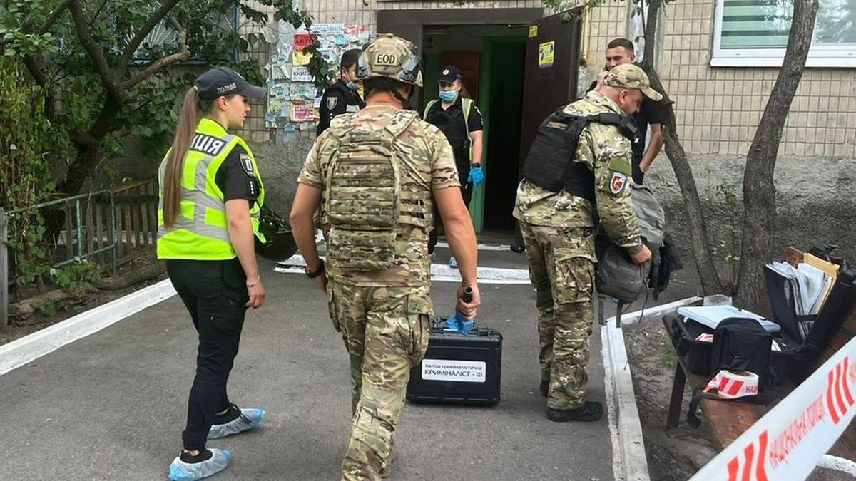 Група поліцейських та військових у камуфляжній формі працюють біля під’їзду багатоповерхівки