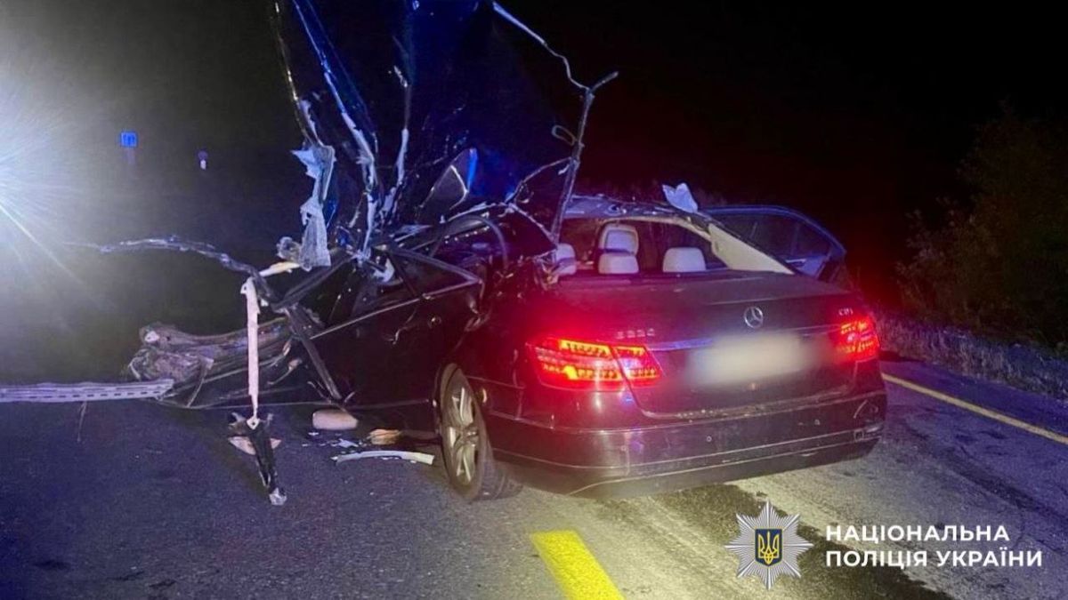 Зруйнована автівка Mercedes після аварії на київській трасі вночі, зображення аварійної ситуації з пошкодженою машиною та спецзасобами поліції на місці події.