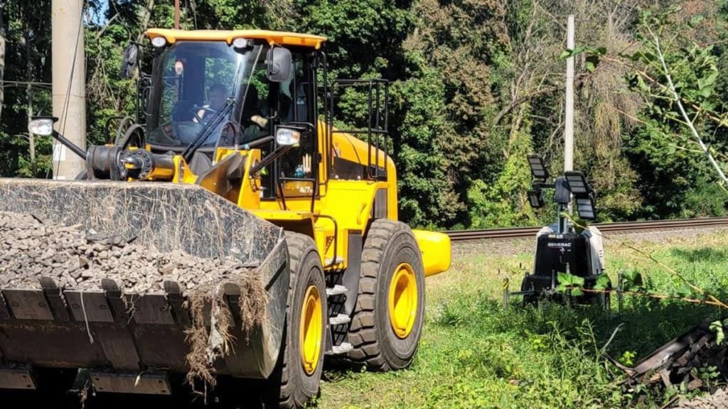 ДСНС і Укрзалізниця показали, як відновлюють рух після вибухів під Києвом (фото) Жовтий навантажувач із щебенем біля залізничної колії