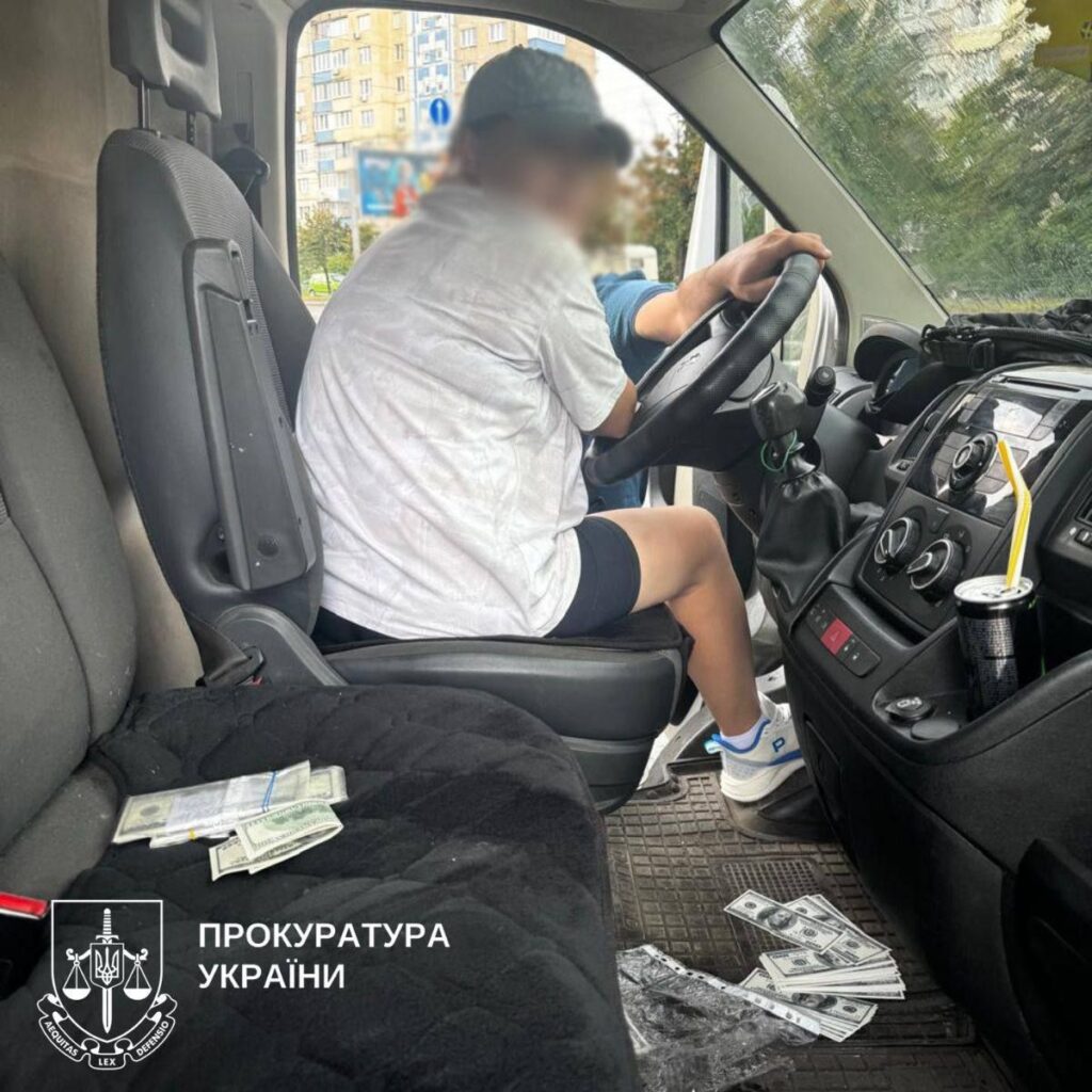 Жінка за кермом мікроавтобуса, всередині якого розкидані долари