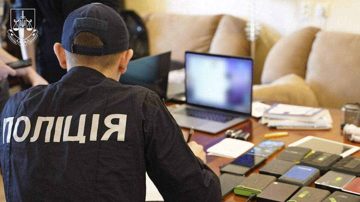 Україна спільно зі США та ЄС знешкодила угруповання кіберзлочинців Поліцейський проводить слідчі дії, на столі перед ним — техніка та документи