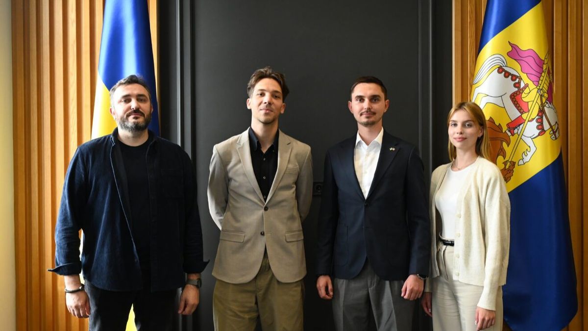 Представники Київщини та французького регіону Іль-де-Франс стоять у ряд на фоні чорної стіни між прапорами України та Київщини