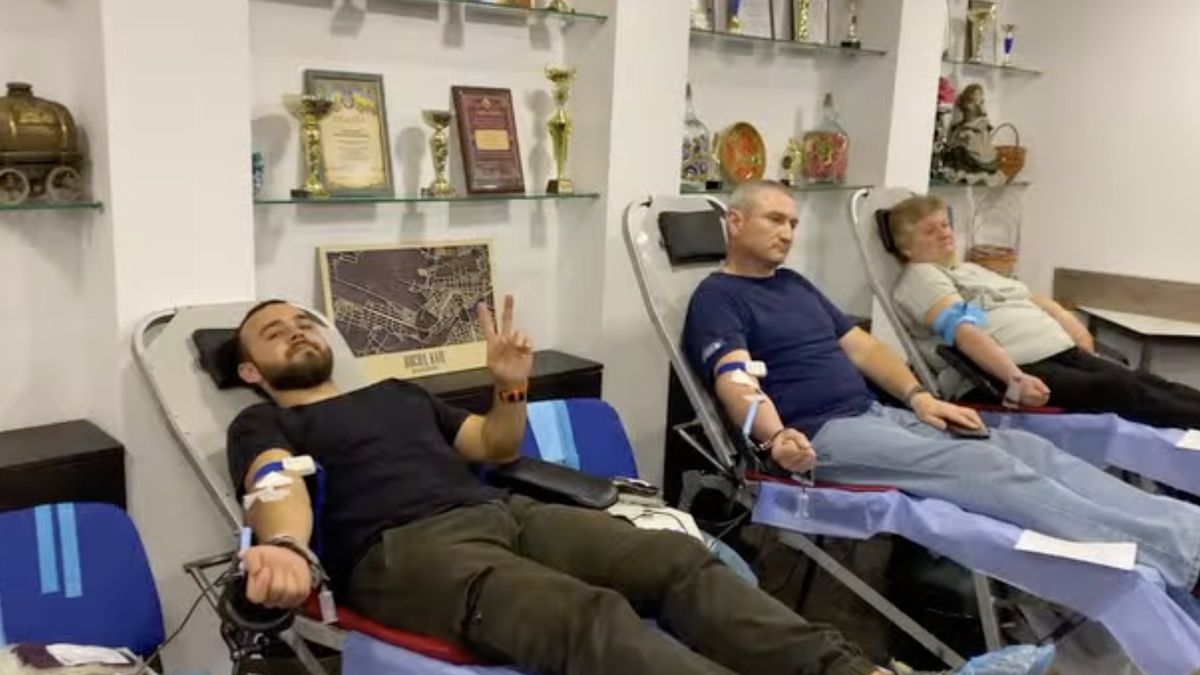 Троє людей лежать на кріслах у приміщенні та здають кров