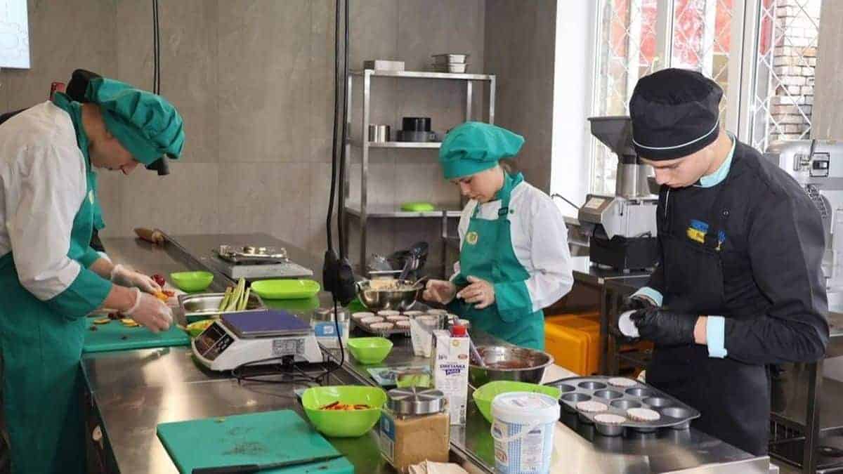 Троє кухарів у зеленій та чорній формі працюють на кухні