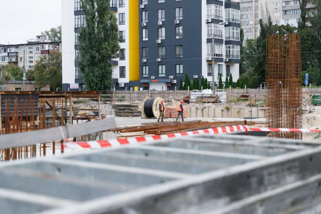 Двоє робітників біля великого котка кабелю серед будівельного майданчика укриття