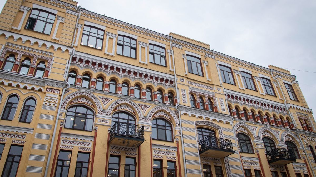 Фасад історичної будівлі в жовто-білих тонах із декоративними арками та балконами з кованими огорожами