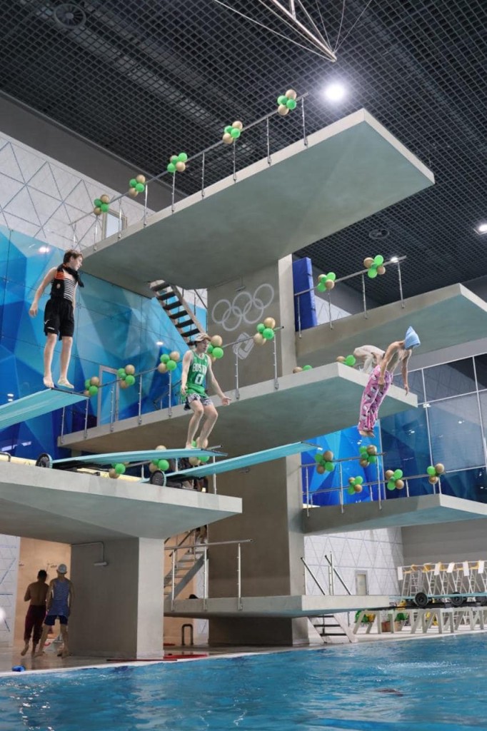 Молоді спортсмени готуються до стрибків із різних рівнів вишки з трамплінами