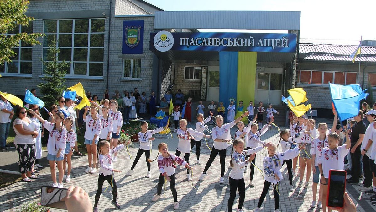 Єдина подія у Києві: діти у традиційному вбранні проводять святковий флешмоб із прапорами України на фоні школи Щасливський ліцей. У заході беруть участь учні та вчителі. Громадськість спостерігає і підтримує учасників у патріотичному заході.