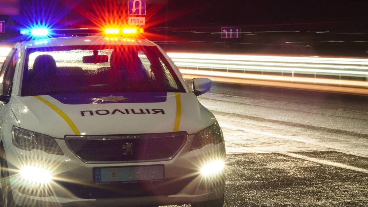 Поліцейський автомобіль із ввімкненими проблисковими маячками синього та червоного кольору стоїть на дорозі вночі