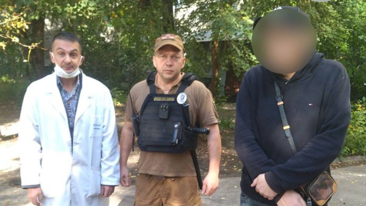 Троє чоловіків стоять на вулиці: лікар, муніципальний охоронець і чоловік у темній толстовці