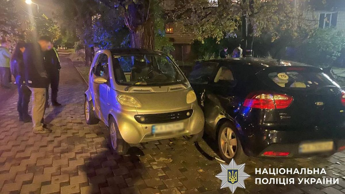 На нічній вулиці зіткнулися два легкові автомобілі, біля яких працюють поліцейські та стоять очевидці