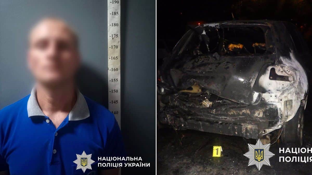 Чоловік у синій футболці стоїть біля стіни з вимірювальною шкалою зросту, його обличчя розмите; поруч згорілий автомобіль уночі з пошкодженим кузовом