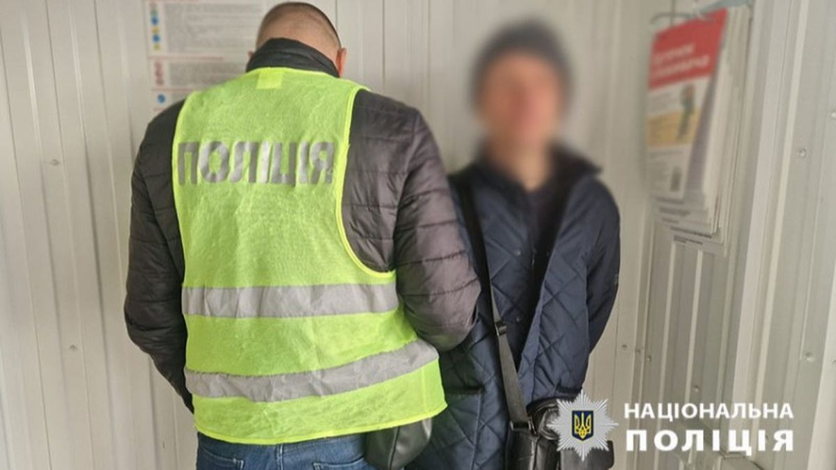 Поліцейський у жовтому жилеті розмовляє з затриманим у приміщенні