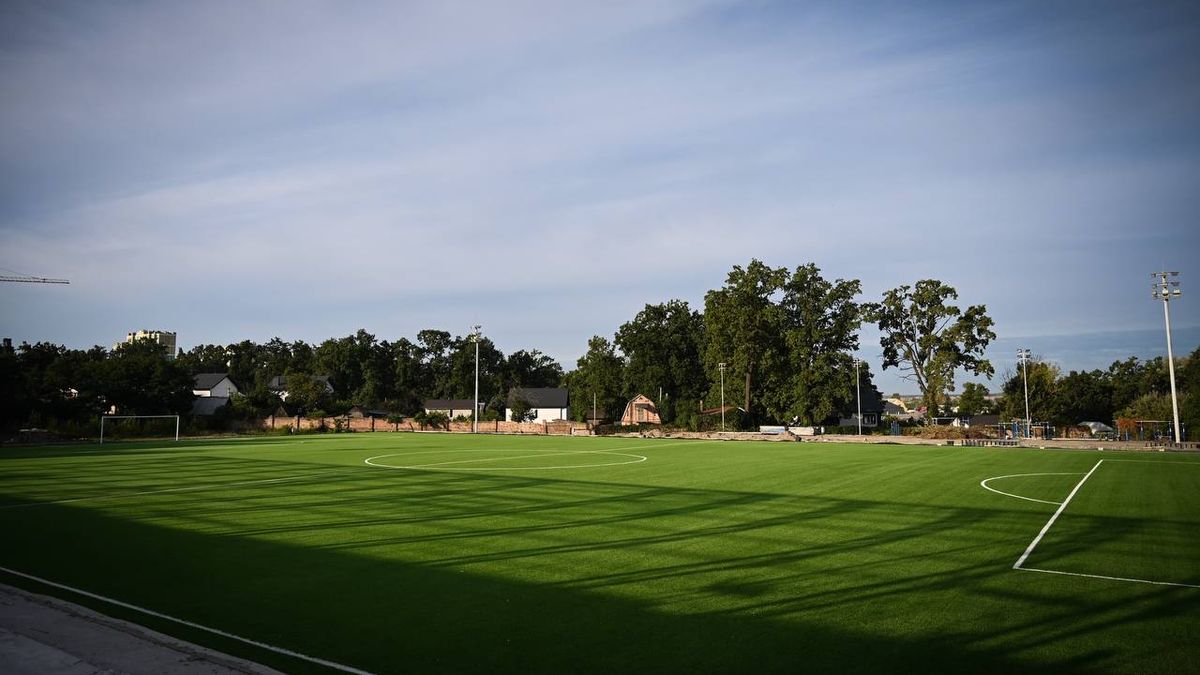 Нове футбольне поле зі штучним покриттям, освітлювальними щоглами та деревами на задньому плані