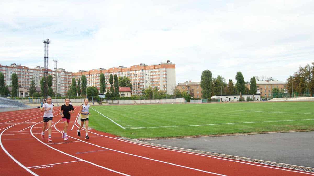 троє дітей шкільного віку на стадіоні біжать