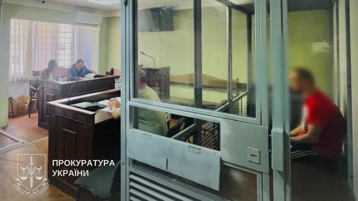 Судове засідання, підозрюваний у червоній футболці перебуває у скляній клітці