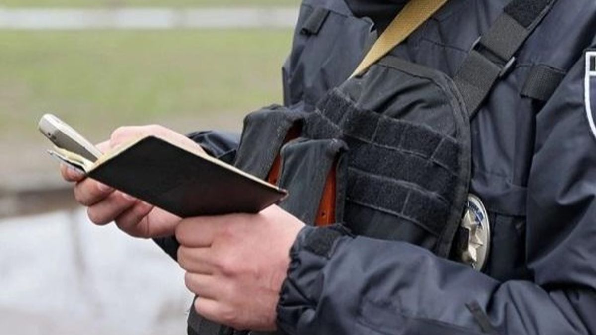 Застережний поліцейський у формі з рацією і блокнотом на вулиці в Києві.