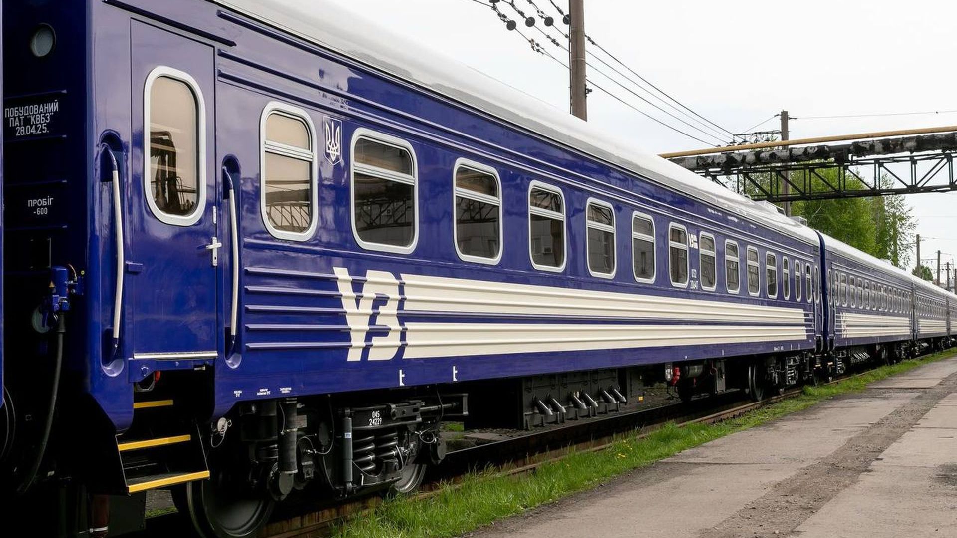 Синій пасажирський вагон «Укрзалізниці», що стоїть на залізничній колії