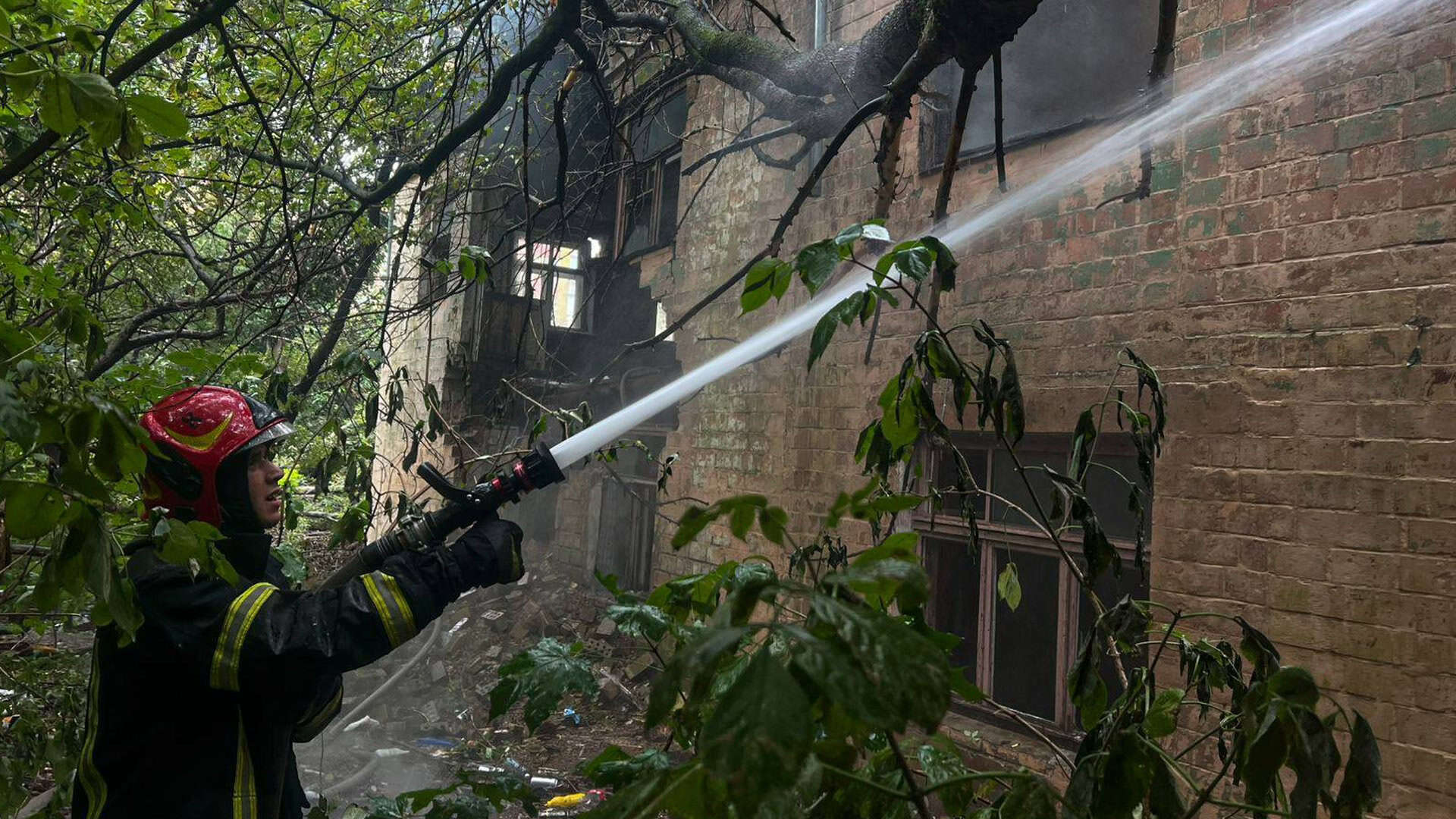Пожежник гасить пожежу, тримає гідрант, з якого йде вода