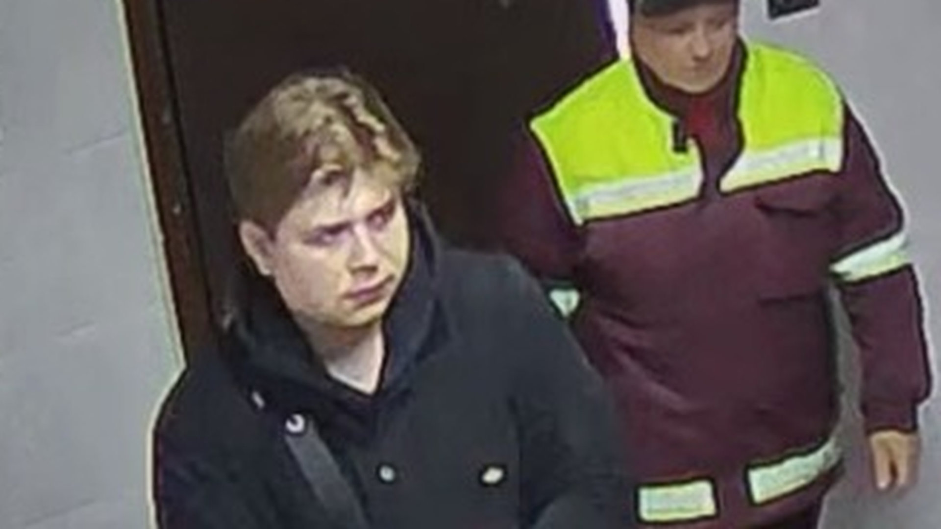 Фотографія чоловіка в під'їзді будинку поряд з іще одним чоловіком в костюмі працівника комунальних служб