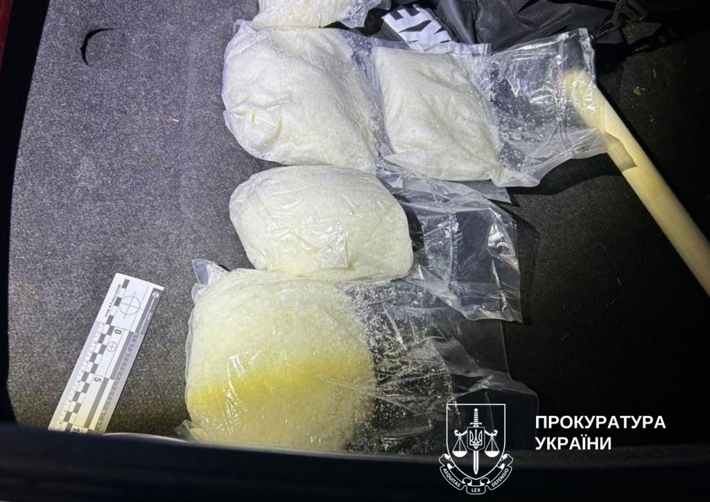 Чотири пакета наркотичної речовини біло-жовтого кольору лежать на сірій поверхні
