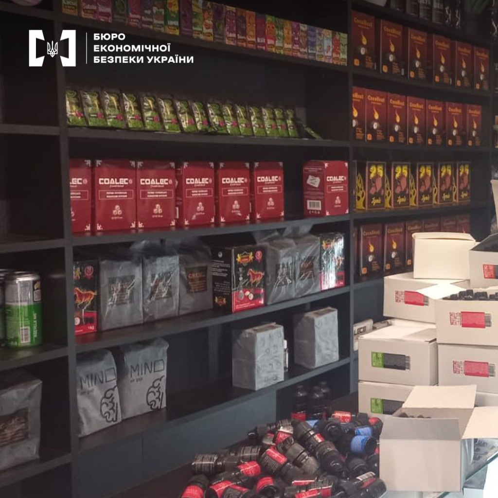 Пʼять полиць із тютюновою продукцією, на підлозі також гора баночок із тютюновою продукцією