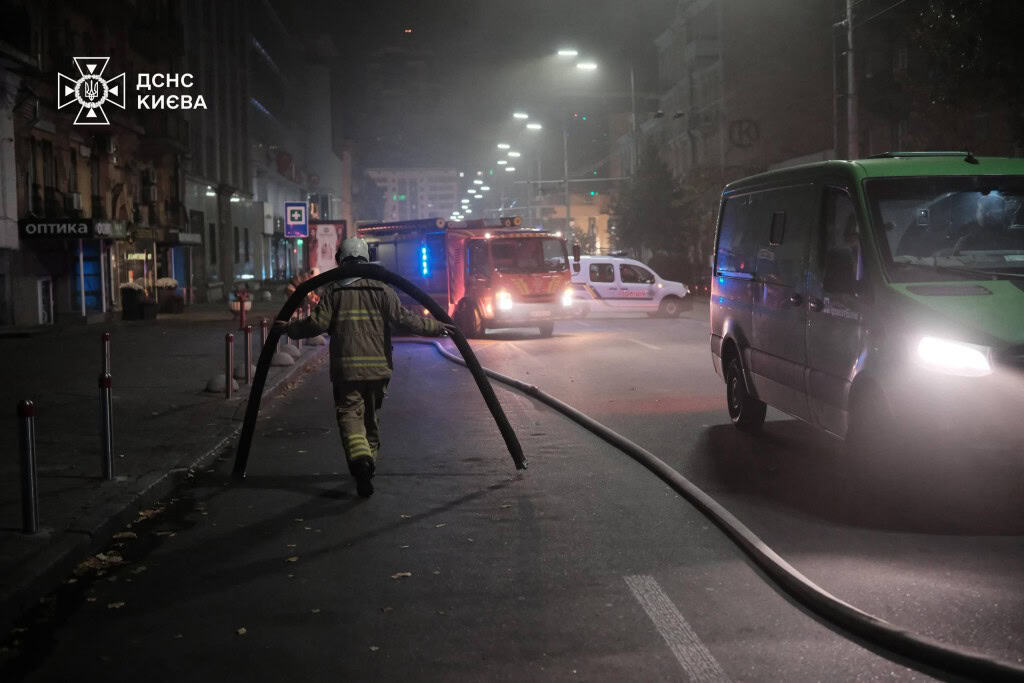 Пожежа в центрі Києва: залучили вже 100 рятувальників Рятувальник несе на плечах важкий шланг пожежного гідранта