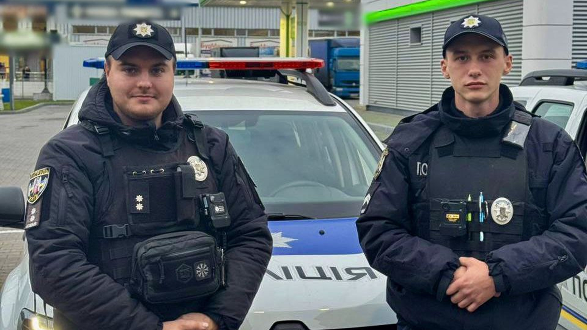 Двоє поліцейських стоять біля службового автомобіля