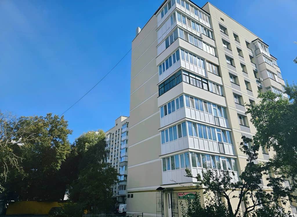 Бежева багатоповерхівка в Бучі з білими пластиковими лоджіями