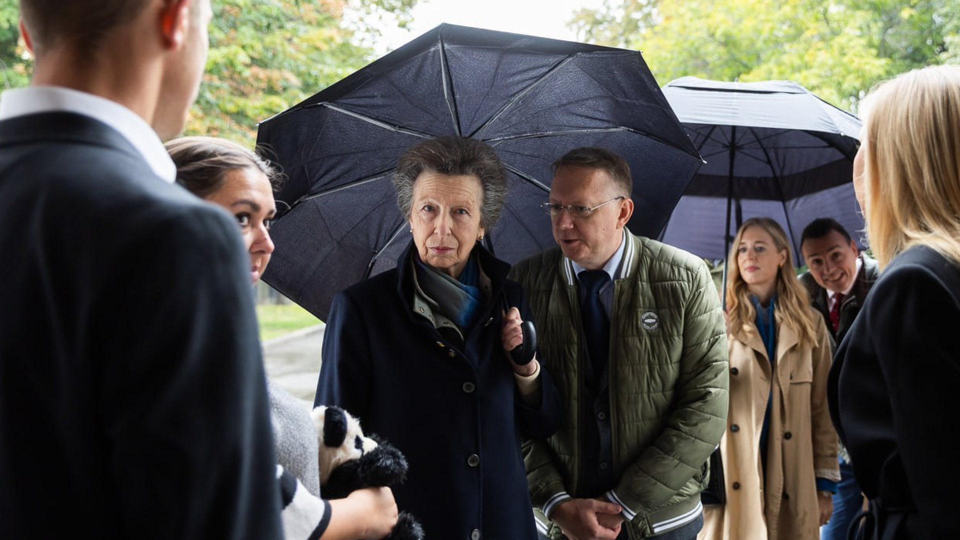 Принцеса Анна на вулиці під парасолькою в оточенні 5 людей