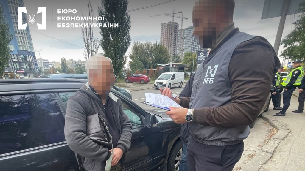 Переховувався 10 років: у Києві затримали виробника спирту Працівник БЕБ зачитує щось з паперів які тримає в руках чоловіку із заблюреним обличчям на вулиці в Києві